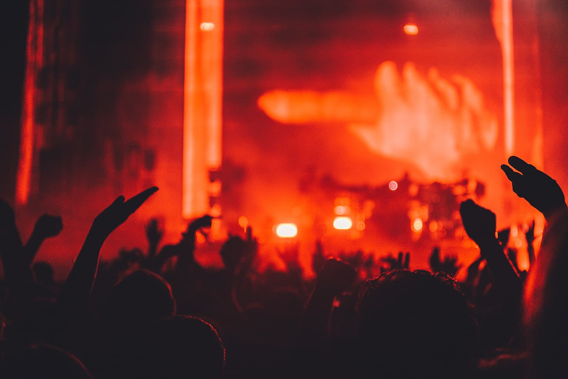 Hands raised in a concert crowd under stage lights