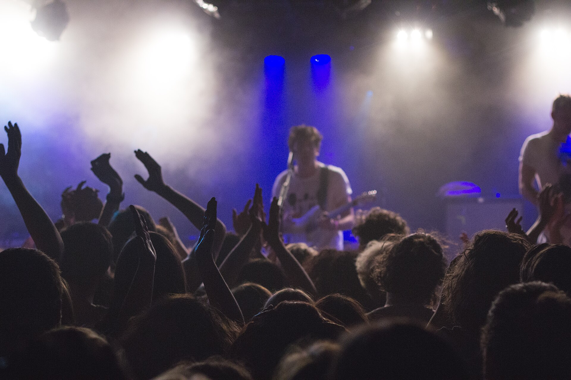A concert crowd with hands in the air in front of the stage